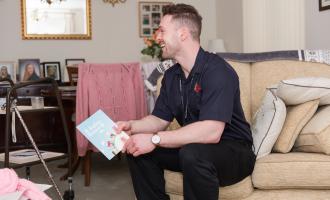 A home fire safety office sits on sofa in living room, offering safety advice