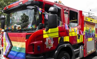 Fire engine decorated with rainbow bunting and flag for pride. 