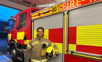 Firefighter Keegan Johnson in front of a fire engine at Stansted Fire Station