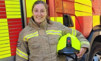 Firefighter Jennifer Adelle standing in front of a fire engine with her helmet