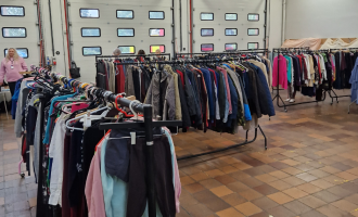 Clothes on racks at fire station being given away to people 