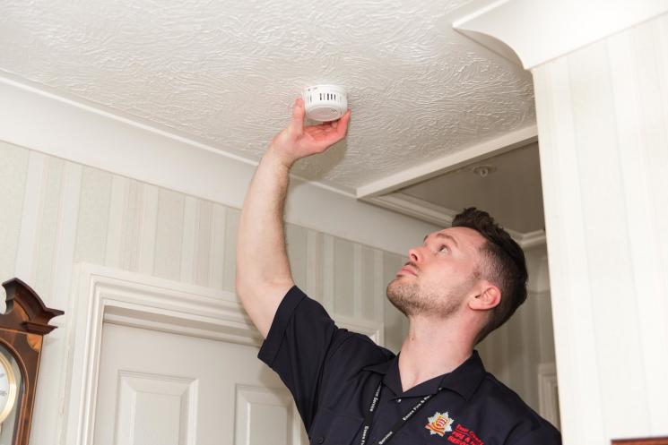 Community Safety Officer fits smoke alarm to the ceiling