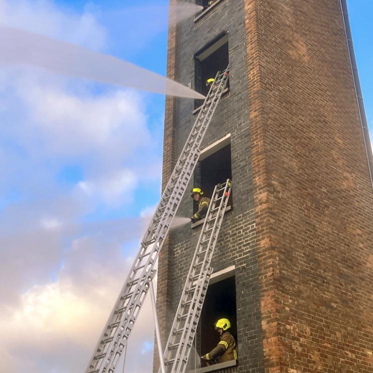 Firefighters practicing with water hoses in training tower