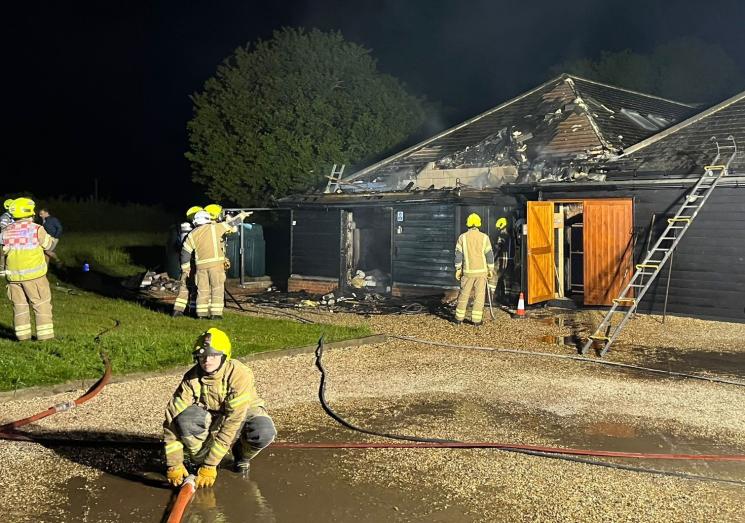 Firefighters outside a single storey building damaged by fire