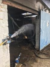 Hose pouring water into the outbuilding