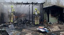 Firefighters in the charred remains of an outbuilding
