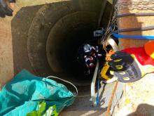 Firefighters using ropes inside a well to rescue a man