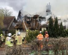 Firefighters at the scene of a thatched roof fire