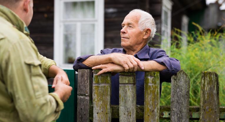 Two neighbours chatting over a fence