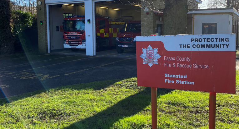 Stansted fire station in the background and a red sign with the name of the station in the foreground 